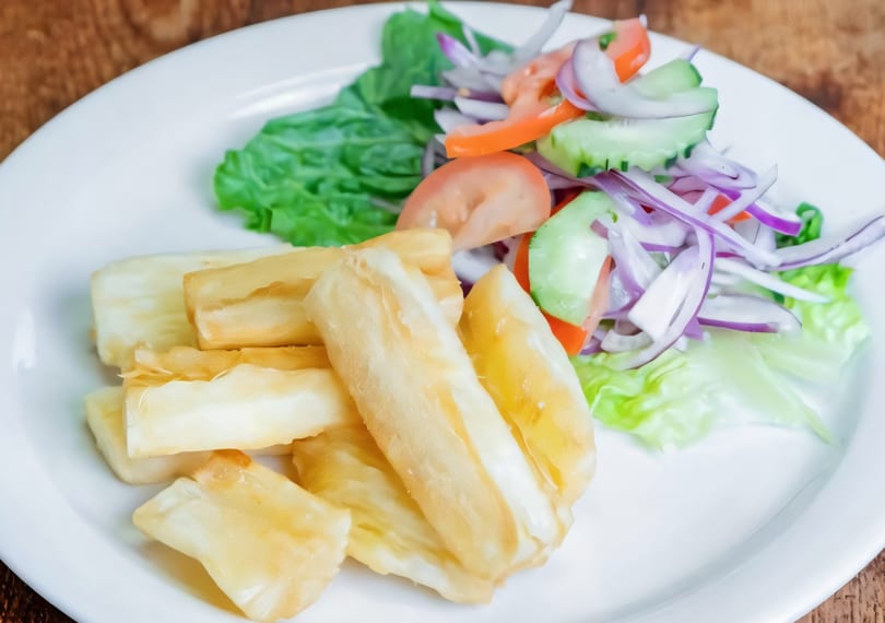 Fried yucca sticks and a fresh salad with lettuce, tomatoes, cucumbers, and red onions.